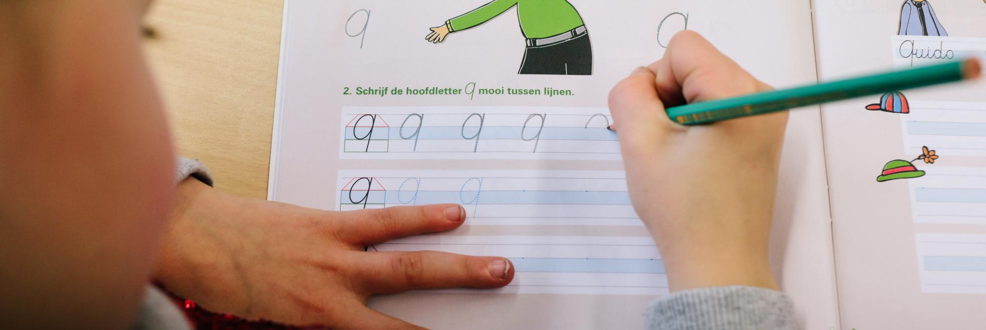 Kind oefent met schrijven van hoofdletter Q